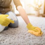 housewife cleaning carpet with brush and doing housework